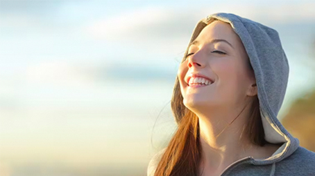 Woman in hoodie with sunshine on her face